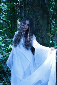 Beautiful woman wearing a long white dress in a forest