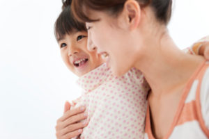 Woman embracing daughter, smiling, white background