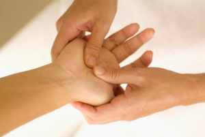 One person's hand inside another's, with fingers pressing on palm